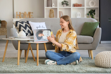 Young woman with cup of tea reading beauty magazine at home