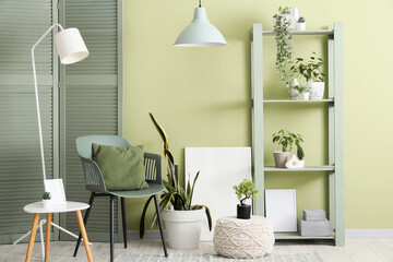 Interior of stylish modern room with armchair, shelving unit and coffee table near green wall