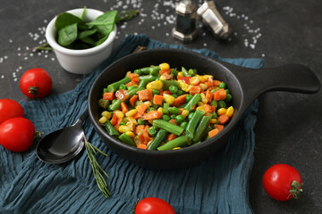 Frying pan with tasty roasted vegetables on black background