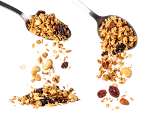 Two spoons overflowing with granola, raisins, and nuts