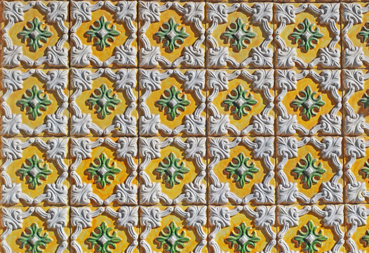 Close-up of traditional Portuguese ceramic tiles with embossed yellow, green and white patterns. Classic azulejos texture with ornamental relief. For backgrounds, prints, packaging, or design.