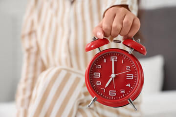 Young woman with alarm clock in bedroom, closeup