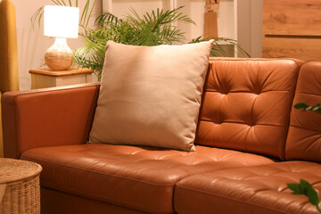 Interior of modern living room with brown sofa, cushion and glowing lamp at evening