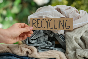 Female hand with heap of natural clothes for recycling outdoors