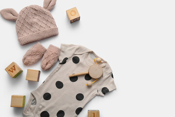 Composition with baby clothes and wooden toys on light background