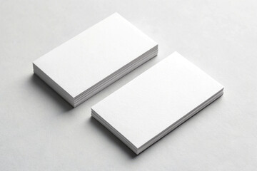 Two stacks of blank white business cards on a light gray surface with soft shadows