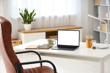 Workplace with blank laptop and cup in office