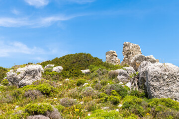 Stacked rocks stack ancient ruins at hiking trail footpath on hill to Greek Drakano tower on Ikaria island, Greece