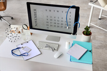 Computer monitor with calendar and doctor's supplies on desk in medical office