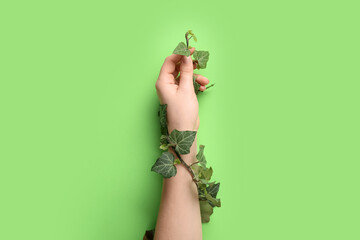 Female hand with plant leaves on color background. Green technology concept