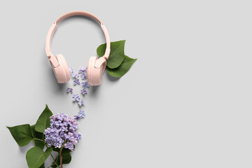 Headphones with lilac flowers on light background. Green technology concept