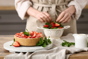 Woman with fresh berries and sweet strawberry tart in kitchen, closeup