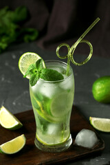 Glass of fresh Mojito cocktail with lime and mint on black background