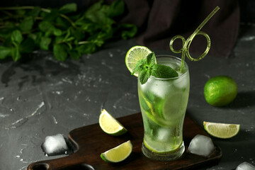 Glass of fresh Mojito cocktail with mint and ice cubes on black background