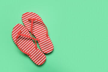 Stylish flip-flops on green background, closeup
