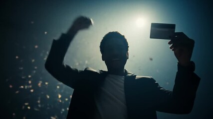 Man Celebrates with Credit Card Under Spotlight