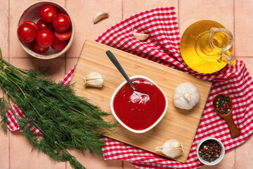 Bowl of tasty ketchup with garlic and dill on beige tile background