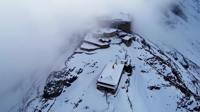 Aerial view of a building covered with snow in the middle of mountain