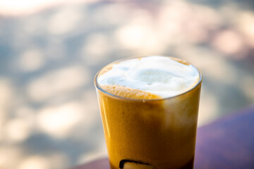 Freddo cappuccino espresso coffee drink beverage in glass macro of foam texture at sidewalk street cafe restaurant of Ikaria Greek island, Greece