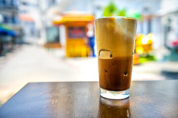 Freddo cappuccino espresso coffee drink beverage in glass on table at sidewalk street cafe restaurant of Ikaria Greek island, Greece