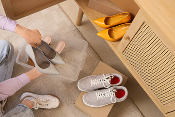 Woman keeping her shoes in chest of drawers at home, top view