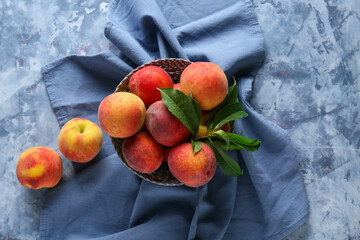 Bowl of fresh peaches on blue background, top view