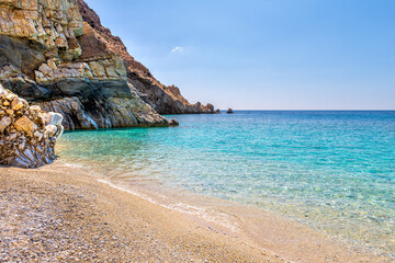 Seychelles beach at Magganitis, Ikaria island Greece, Icarian sea of crystal clear green turquoise water, rocky cliffs coast water level view
