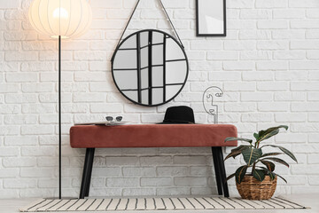 Pink bench, floor lamp, mirror and houseplant in interior of room
