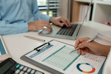 the company's statistics department staff is checking the figures form the graph in the document for recording, accounting, finance, marketing, entrepreneur, paperwork, office