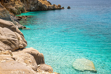Seychelles beach at Magganitis, Ikaria island Greece, Icarian sea with crystal clear green turquoise water, rocky cliffs coast above view