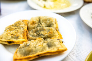 Pitarakia green pies on Ikaria island, Greece with horta wild greens herbs deep fried dish on white plate macro closeup