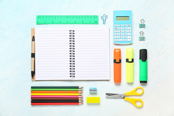 Composition with open blank notebook and stationery supplies on blue grunge background, closeup