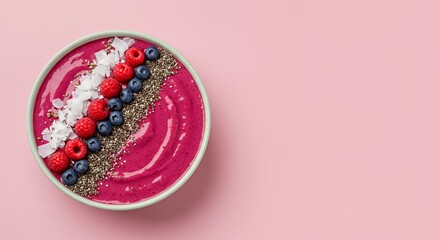 Indulge in a vibrant pink smoothie bowl, adorned with fresh raspberries, blueberries, chia seeds, and shredded coconut, a delightful and healthy breakfast or snack.