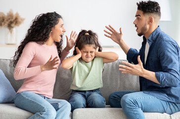 Parental Quarrels. Arab Man And Woman Arguing In Front Of Their Child, Upset Little Girl Covering...
