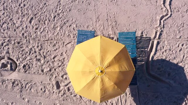 Beach aerial reveal from umbrella and chair 4k
