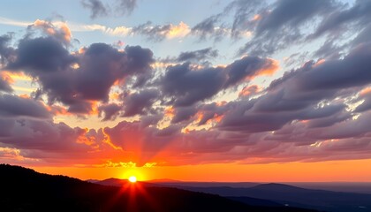 stunning sunset, with the sun peeking through the clouds, casting a warm glow over the mountain range and the sky