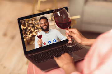 Celebrating Anniversary. Back over the shoulder view of young black woman having a romantic online date with her man, holding glass of red wine and toasting with computer on her lap. Stay Safe