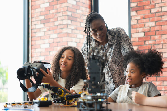 Teacher Guiding Girls in Robotics and VR Class, Young Students Exploring Technology with Virtual Reality and Robotics, STEM Education Diverse Girls Learning About Engineering and Innovation