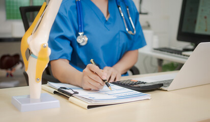 A middle-aged Asian female doctor at her desk,explaining various bone and joint diseases like...