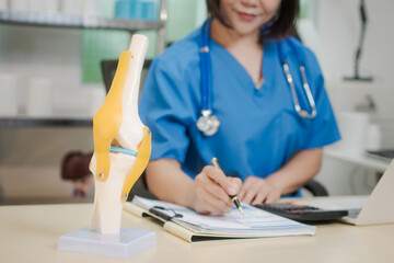 A middle-aged Asian female doctor at her desk,explaining various bone and joint diseases like...