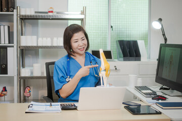 A middle-aged Asian female doctor at her desk,explaining various bone and joint diseases like...