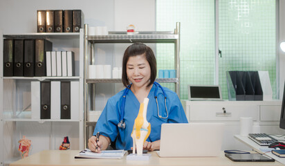 A middle-aged Asian female doctor at her desk,explaining various bone and joint diseases like...