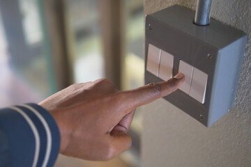 Person pressing a switch on a wall in a building