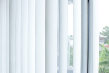 Bright White Vertical Blinds Filter Daylight Through Window With Blurred Outdoor View
