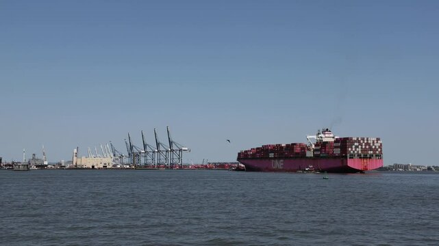View of container ship docked off the coast of Bayonne New Jersey with cranes in the background.