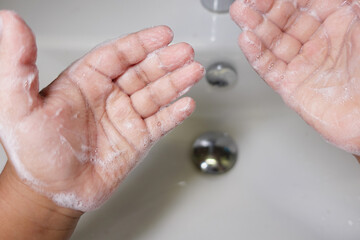 Child Washing hands with soap at a bathroom sink