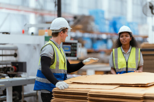 Professional worker team in safety uniform, supervisor inspector in packaging stock order at cardboard factory warehouse, piles of stacking paper manufacture, recycling industrial production