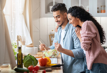 Cooking Together. Happy millennial middle eastern couple preparing food in kitchen, smiling young...