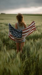 Wind swayes U.S. flag in the hands of a woman standing on a green wheat field.,4 July , USA