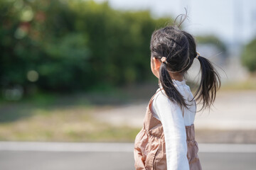 A 3-year-old Japanese girl with twin-tails runs happily through a quiet countryside road. Captured...